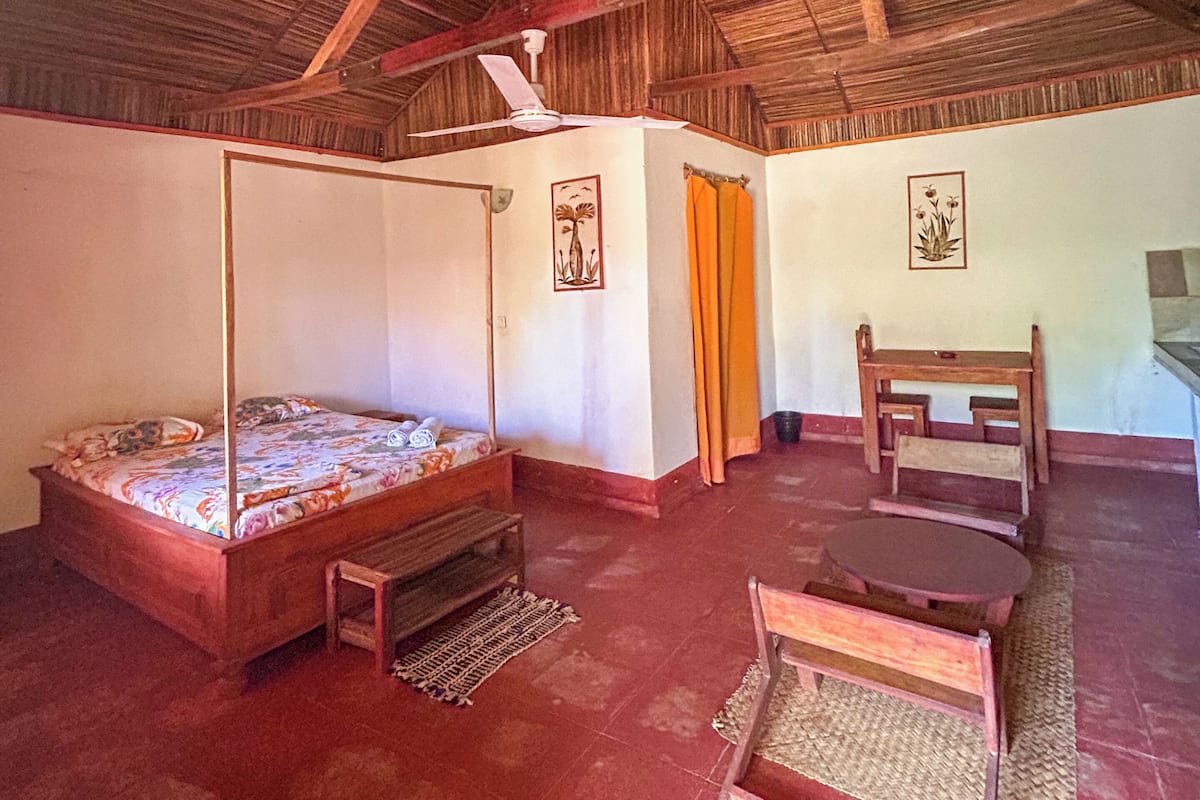 Une pièce avec un plafond en bois, un lit à baldaquin, une table en bois et une chaise.