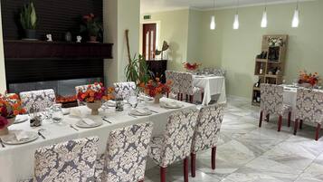 Un espace repas avec une longue table dressée pour le repas, entourée de chaises aux motifs variés.