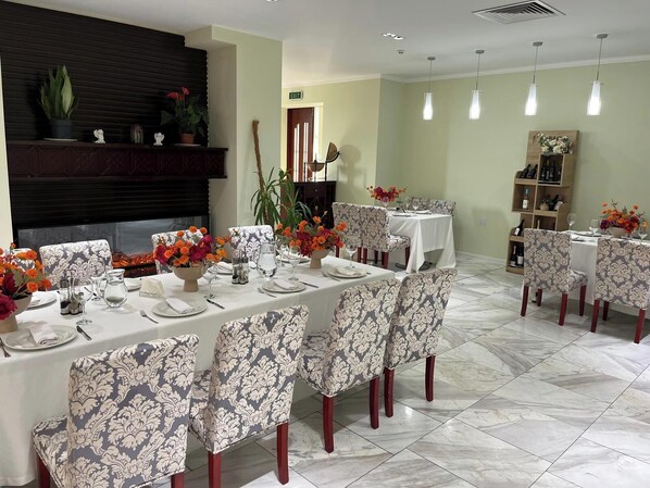 Un comedor con una larga mesa dispuesta para una comida, rodeado de sillas con diseños.