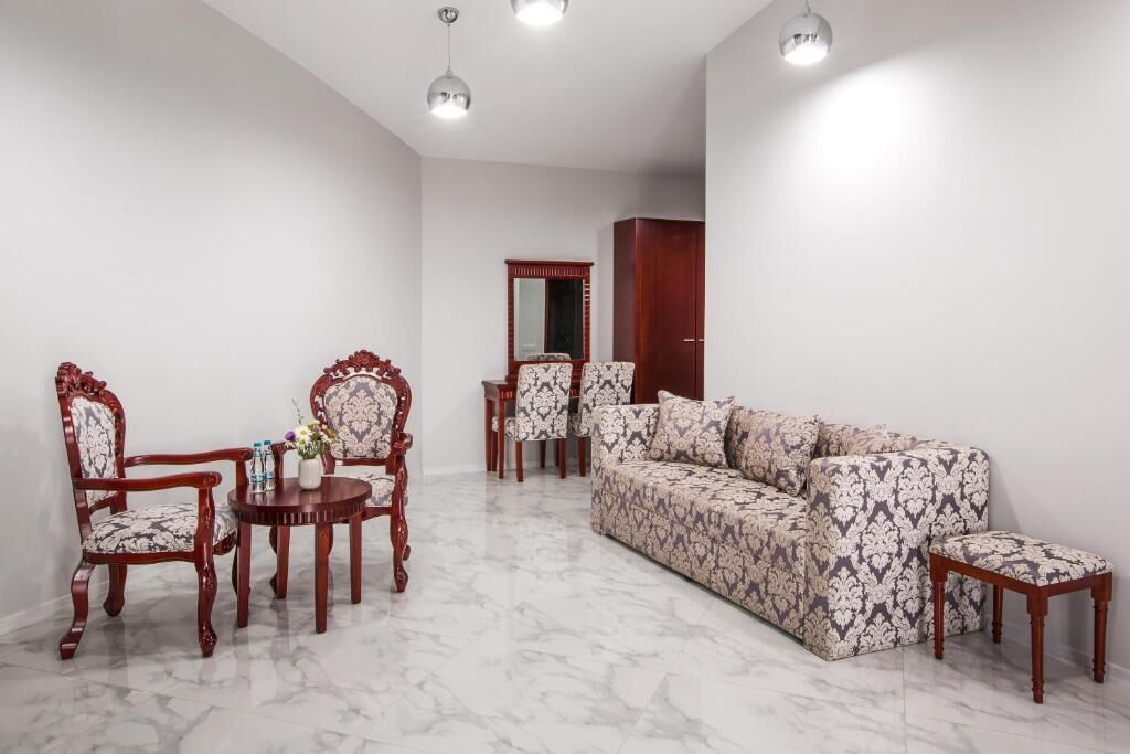 Una sala de estar con un sofá, dos sillones, una mesita de centro y una mesita auxiliar con objetos decorativos.