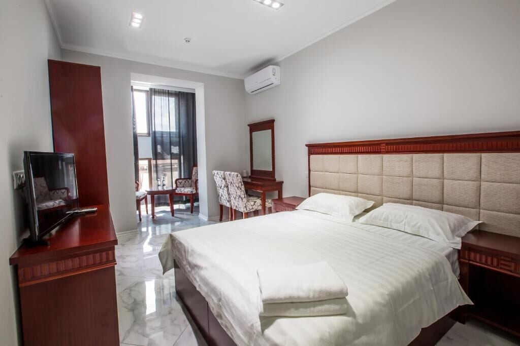Ein Hotelzimmer mit Bett, Fernseher, Schreibtisch und Stuhl.