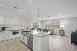 A modern kitchen with white cabinetry, a central island, and a dining area with a sofa and table.