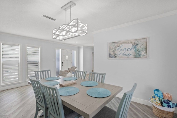 A dining room with a wooden table, blue chairs, and a decorative light fixture.