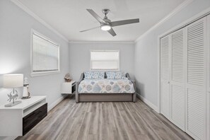 Une chambre à coucher comprenant un lit, un ventilateur de plafond, une table de chevet, une lampe et une armoire.