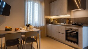 A modern kitchen with a built-in oven, a sink, and a flat-screen TV mounted on the wall.
