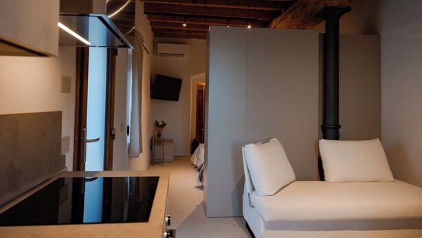 A modern room with a sofa, a flat-screen TV, and a wooden ceiling.