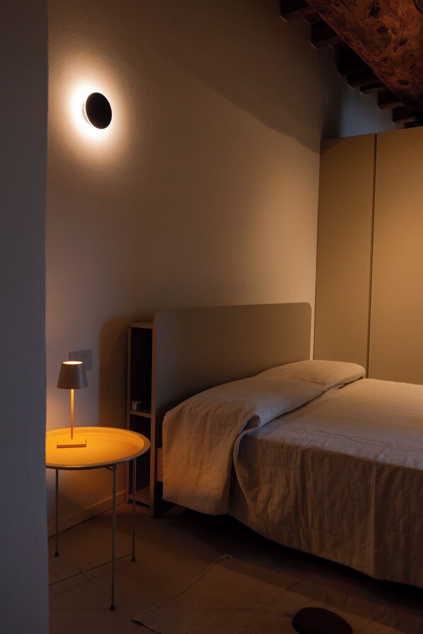 Une chambre à coucher avec un lit, une table de chevet avec une lampe et un luminaire rond fixé au mur.
