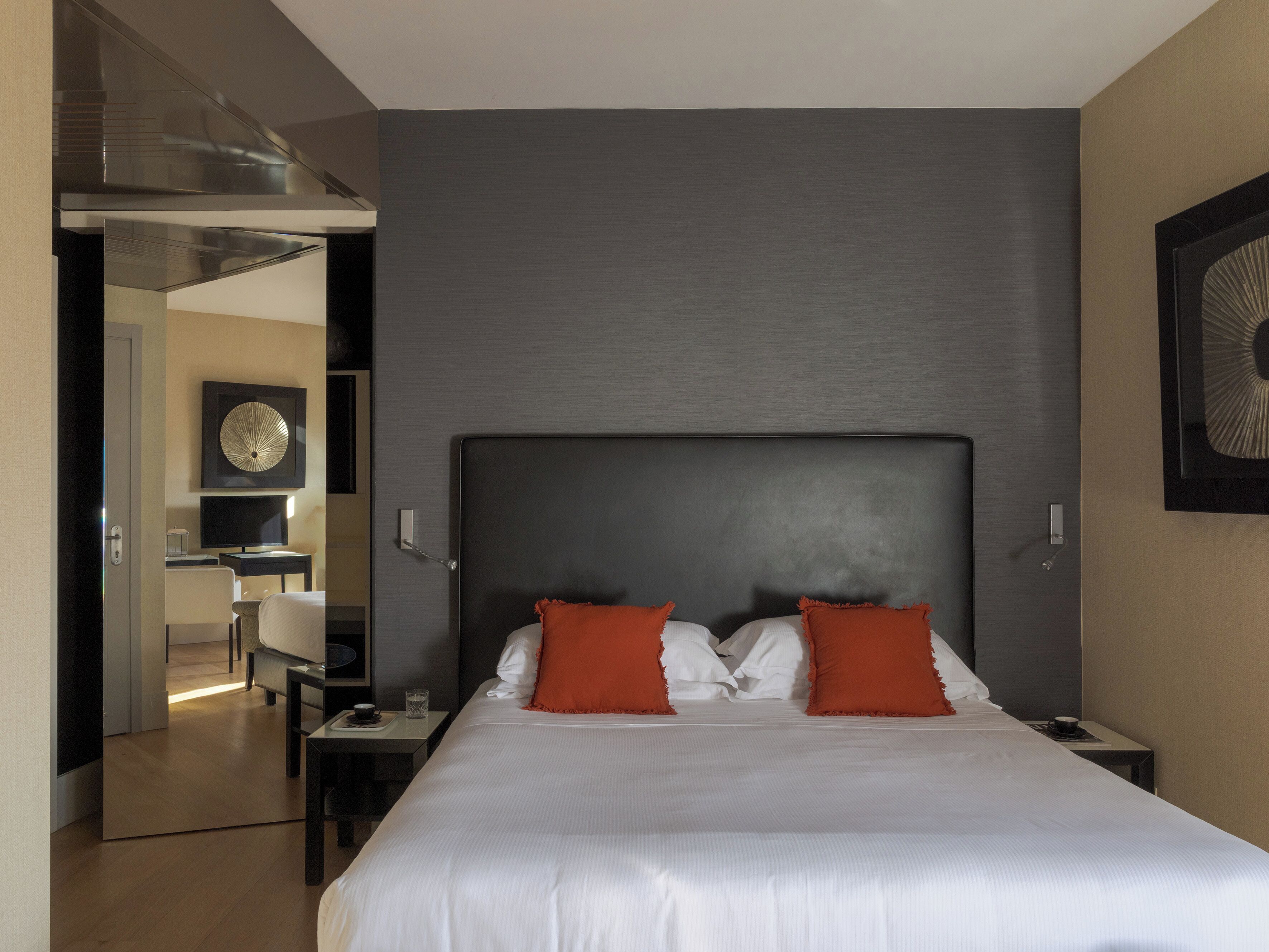 A hotel room with a large bed, a television, a desk, and a modern design.