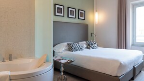 Une chambre d’hôtel moderne avec un grand lit, une baignoire et une petite table.