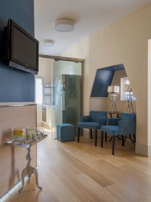 A modern living room with a flat-screen TV, a glass partition, and blue upholstered chairs. - Domus Adriani (Rome)