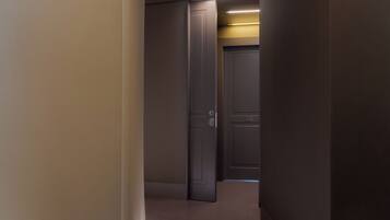 A hallway with a door on the right, a light strip on the wall, and a reflective floor.