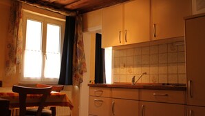 A kitchen with wooden cabinets, a window with curtains, and a tiled backsplash. - Studio '3' with Shared Terrace (Bamberg)