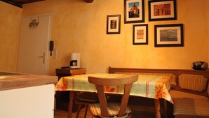 A dining area with a wooden table and chairs, a bench, and a wall with framed pictures. - Studio '3' with Shared Terrace (Bamberg)