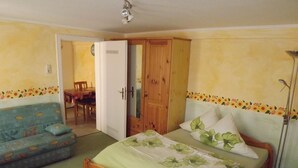 Een slaapkamer met een bed, een houten garderobe, een bank en een eethoek.