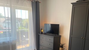 Ett sovrum med en säng, en byrå, en tv och en garderob.