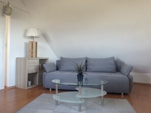 A modern living room with a grey sofa, a glass coffee table, and a wooden cabinet.