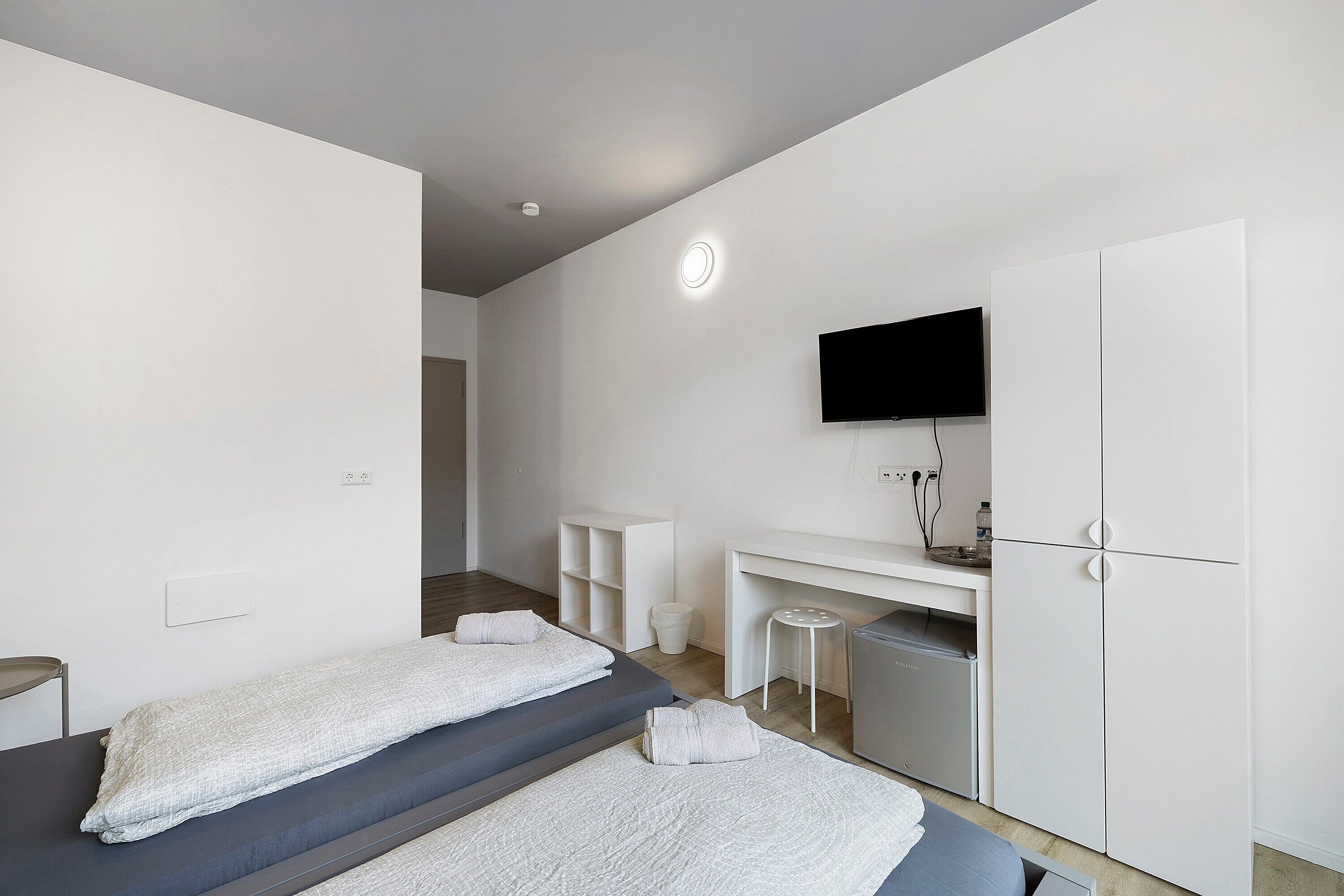 Een moderne hotelkamer met twee bedden, een bureau, een televisie en een kledingkast.