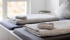 A neatly made bed with folded towels and a window with a view of trees. - Room '5' with Shared Terrace and Wi-Fi (Dußlingen)