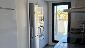 Eine moderne Küche mit Edelstahlgeräten, einer schwarzen Arbeitsplatte und Blick nach draußen durch eine Glastür.