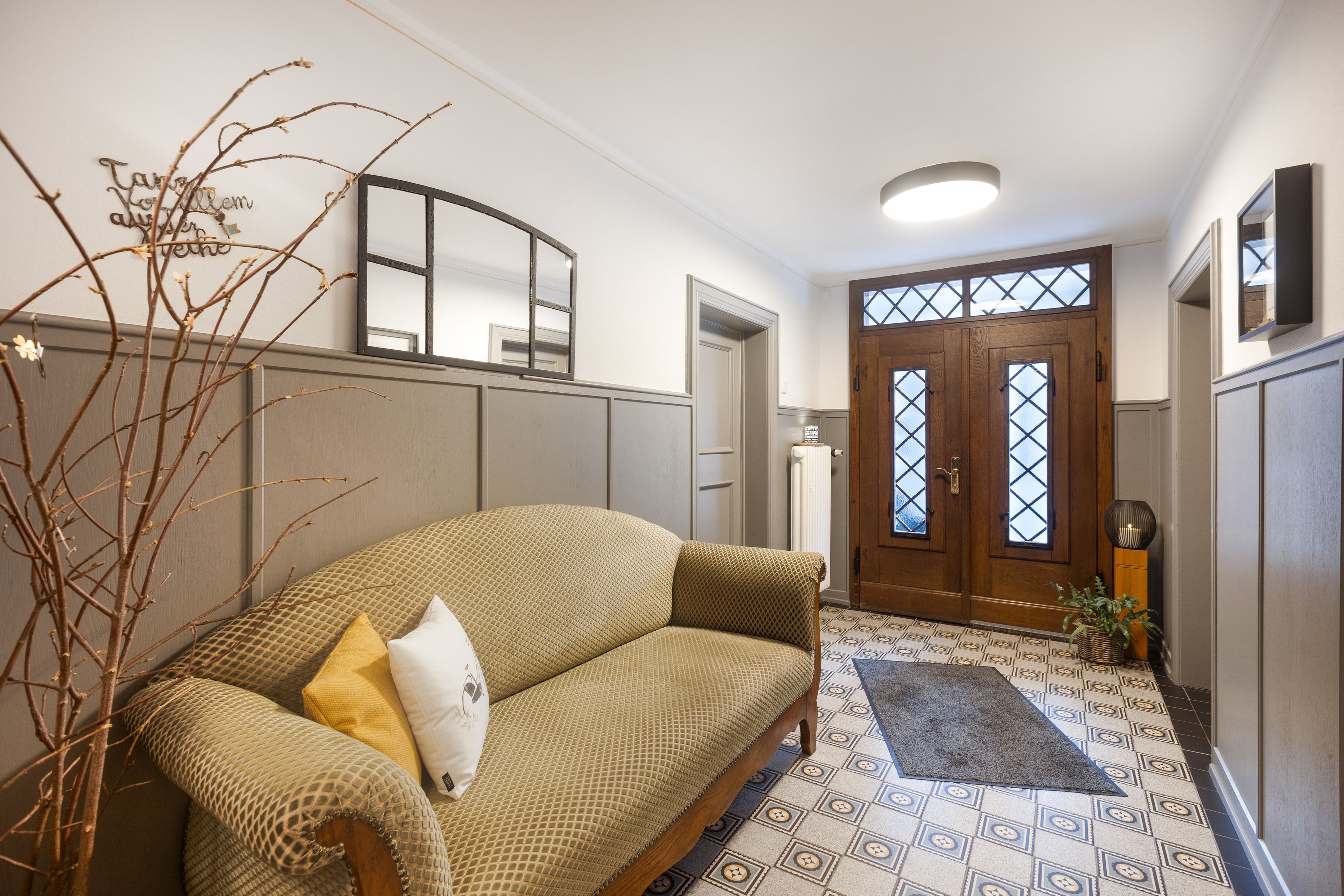 Sala de estar com sofá, galho decorativo e tapete estampado.