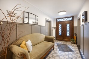 A living room with a sofa, a decorative branch, and a patterned rug.