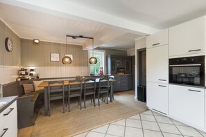 Una cocina moderna con comedor, que incluye un horno empotrado, una isla grande con asientos y un reloj en la pared.