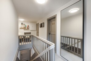 A staircase with a white railing, a door with a nameplate, and a bookshelf with books.