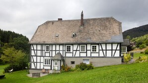 A traditional half-timbered house with a sloped roof, a small porch, and a well-maintained garden.