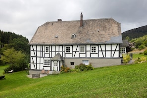 A traditional half-timbered house with a sloped roof, a small porch, and a well-maintained garden.