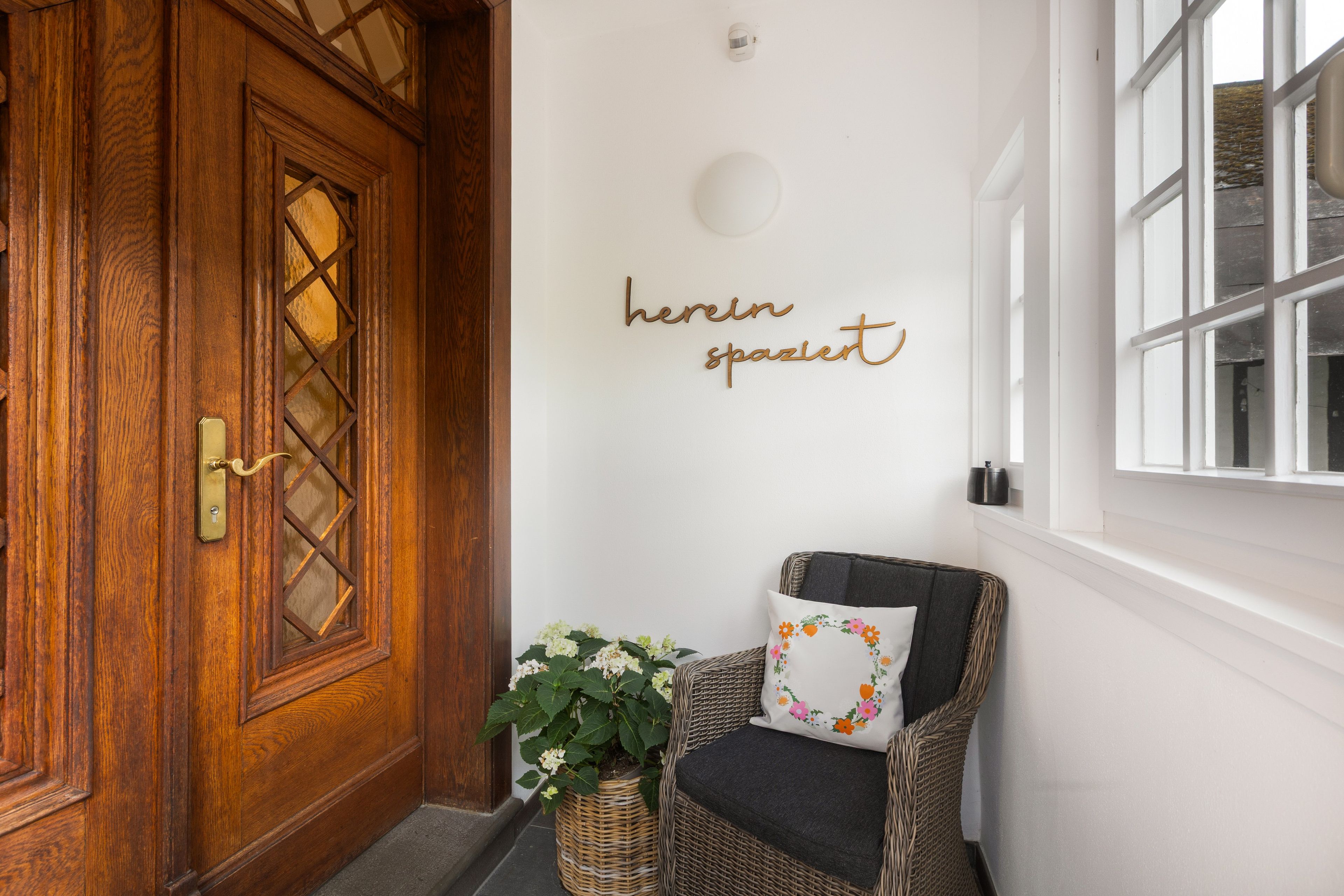 A wooden door with a glass panel, a wicker chair with a cushion, and a wall with a sign.