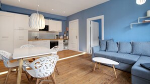 Ein modernes Wohnzimmer mit blauer Wand, grauem Sofa und Holzboden.