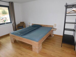 A room with a wooden bed, a chair, a shelf, and a window. - Apartment '4' with Shared Terrace, Shared Garden and Wi-Fi (Gerstungen)