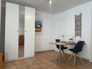 Een eethoek met een tafel, stoelen, een schilderij en een deur naar een andere kamer.