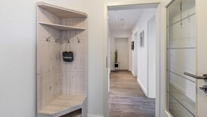 Un pasillo con un banco de madera, un letrero colgante y una puerta con paneles de vidrio esmerilado.