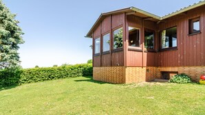 A two-story wooden house with large windows, a brick foundation, and a well-maintained lawn. - Apartment 'Landleben' with Mountain View and Shared Garden (Hofgeismar)