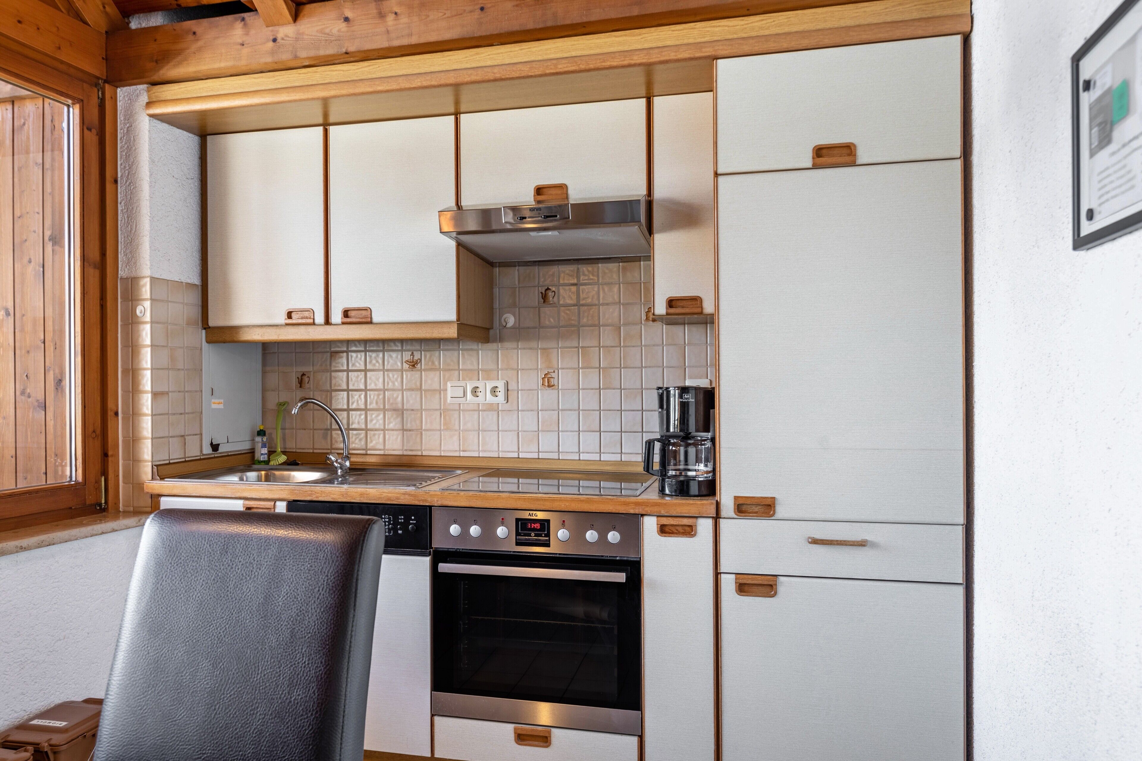 Cocina compacta con horno empotrado, un lavamanos y una cafetera.