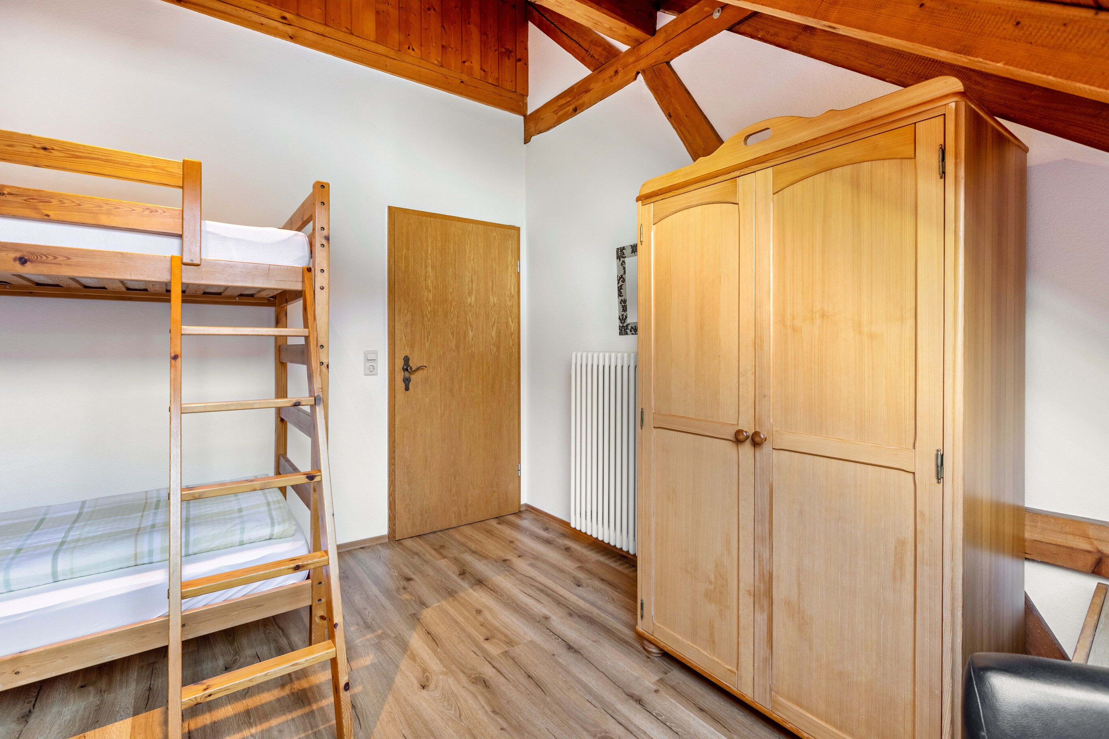 Una habitación con literas, un armario de madera y una puerta.