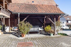 A covered outdoor seating area with potted plants, a metal table, and a bench. - Apartment '2' with Shared Garden, Balcony and Wi-Fi (Bodman-Ludwigshafen)