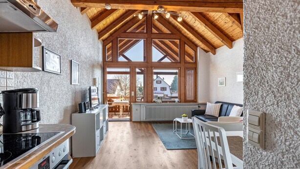 Una cocina amplia con vigas de madera, un comedor con vistas y un rincón de estar acogedor.
