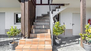 Un edificio moderno con una escalera que sube a un segundo piso, plantas en macetas y un extintor.