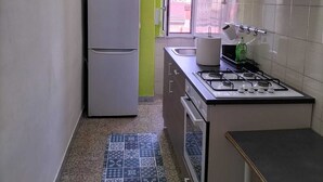 A compact kitchen with a refrigerator, stove, and sink. - Art house - Central station (Napoli)
