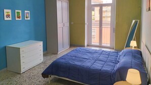 A bedroom with a bed, a wardrobe, a dresser, and a window with a view of the outside. - Art house - Central station (Napoli)