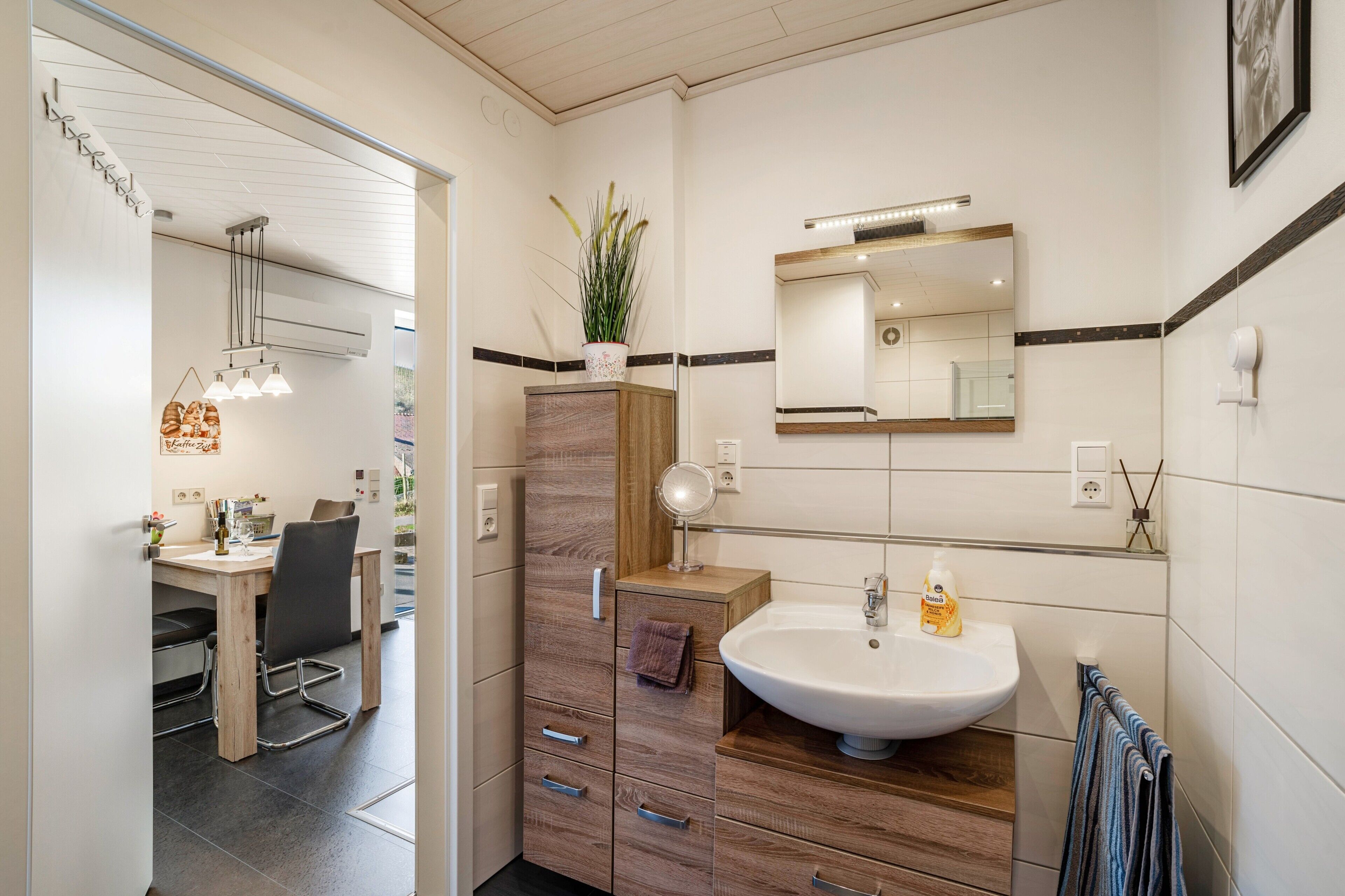 Un baño moderno con lavamanos, espejo y toallero.
