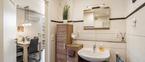 Un baño moderno con lavamanos, espejo y toallero.