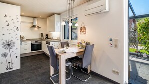 A modern kitchen with a dining area, featuring a stove, oven, and pendant lights. - Holiday Apartment 'Huschle' with Private Terrace, Wi-Fi and Air Conditioning (Kappelrodeck)