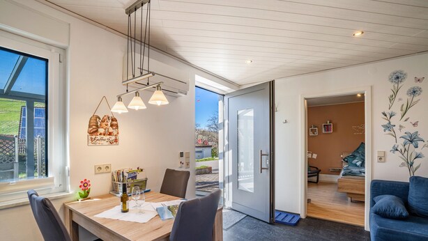 A modern interior with a dining area, a sofa, and a bedroom visible through an open door. - Holiday Apartment 'Huschle' with Private Terrace, Wi-Fi and Air Conditioning (Kappelrodeck)