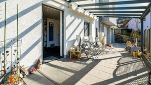 A covered outdoor area with a glass roof, a door leading to a room, and outdoor furniture. - Holiday Apartment 'Huschle' with Private Terrace, Wi-Fi and Air Conditioning (Kappelrodeck)