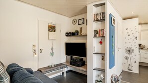 A modern living room with a sofa, a flat-screen TV, a coffee table, and a bookshelf. - Holiday Apartment 'Huschle' with Private Terrace, Wi-Fi and Air Conditioning (Kappelrodeck)