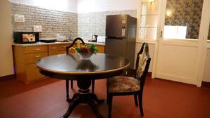 A compact kitchen with a dining table, a refrigerator, and a microwave.