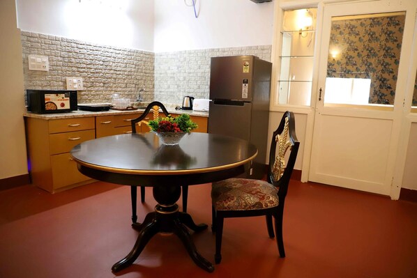 Una cocina compacta con una mesa de comedor, un refrigerador y un microondas.